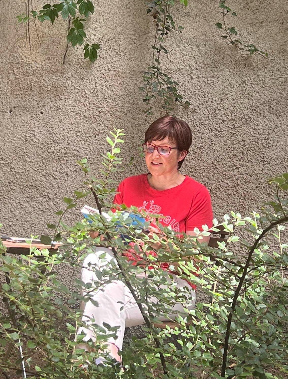 Gabriele Feile liest umgeben von grünen Kletterpflanzen in München