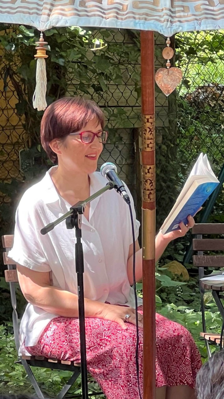 Gabriele Feile sitzt vor einem Mikrofon und liest aus ihrem Buch "Schmetterlinge fallen nicht vom Himmel"